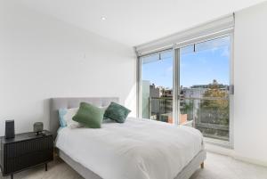 una camera da letto con un letto bianco e una grande finestra di Port Melbourne and a glimpse of the sparkling bay - sleeps 4 a Melbourne