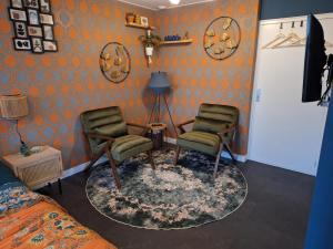two chairs and a table in a room with orange walls at B&B de Gouwe Tijd, suite "Gouden Ginkgo" in Noordgouwe