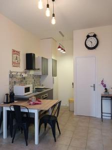 a kitchen with a table and chairs and a clock on the wall at Centre ville-Rue commerçante in Vendôme +5 photos