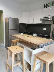 a kitchen with a wooden counter with stools and a refrigerator at charmant appartement au cœur du village in Claret