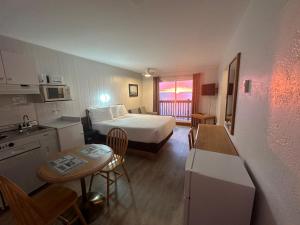 a hotel room with a bed and a table and a kitchen at Motel Carleton Sur Mer in Carleton-sur-Mer