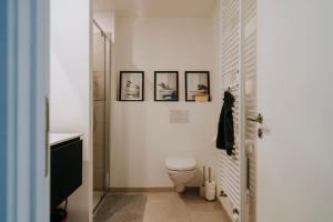 a bathroom with a toilet and three pictures on the wall at 2 bedroom apartment and private parking in Liège center in Liège +15 photos