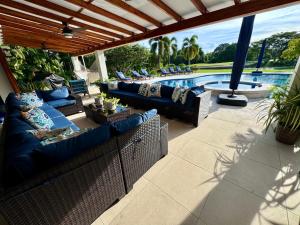 a patio with blue couches and a swimming pool at Villa Solara 6 - Luxury 6 Bedroom Villa with Pool, Golf & Lake View in Río Hato