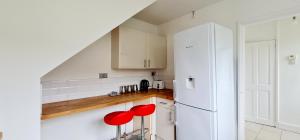 a kitchen with white cabinets and red stools at Love Deluxe Queen Bedroom Manchester in Middleton +37 photos