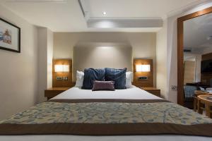 a bedroom with a large bed with blue pillows at Thistle London Piccadilly in London