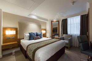 a hotel room with a large bed and a chair at Thistle London Piccadilly in London