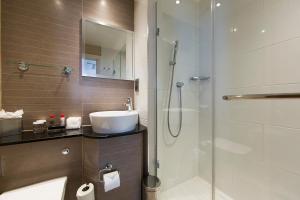 a bathroom with a sink and a glass shower at Thistle London Piccadilly in London