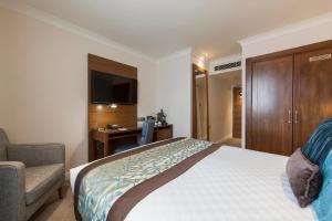 a hotel room with a bed and a chair and a desk at Thistle London Piccadilly in London