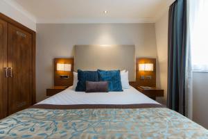 a hotel room with a large bed with blue pillows at Thistle London Piccadilly in London