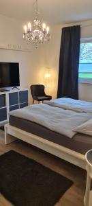 a bedroom with a large bed and a chandelier at Mutti 's Haus -Zur Südheide in Wahrenholz