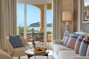 a living room with a couch and a table with a bowl of fruit at Almar Timi Ama Resort & Spa in Villasimius