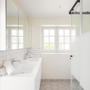 a white bathroom with two sinks and a mirror at Villa Cocquelicot 6p in De Panne +9 photos
