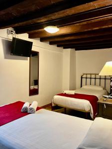 a bedroom with two beds and a television in it at Casa Benalua, Siglo XVI in Granada