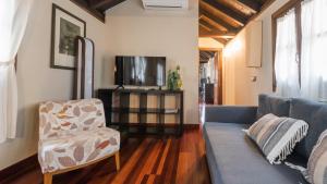 Una sala de estar con un sofá azul y un televisor. en Apartamentos Las Teresitas junto a la Catedral, en Toledo 12 fotos más