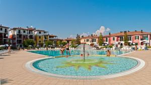 Una fuente en medio de una plaza con gente alrededor. en Villaggio Sant'Andrea, en Caorle