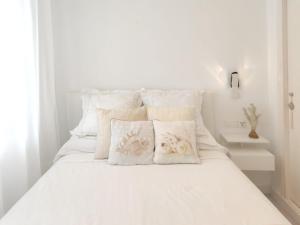een wit bed met witte kussens erop bij QBF Quality Beachfront in Torre del Mar