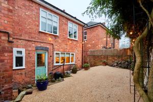 Fig Tree House في غْريت مالفيرن: مبنى من الطوب مع باب أزرق وفناء