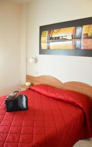 a bedroom with a red bed with a red comforter at Albergo Aurora in Castenaso