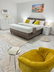 a bedroom with a large bed and a yellow chair at Apartmani Ikanović in Cazin +34 photos