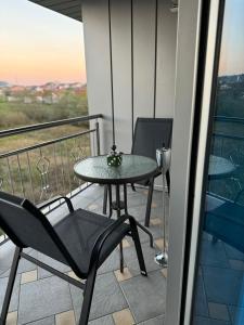 a table and chair on a balcony with a view at Apartmani Ikanović in Cazin