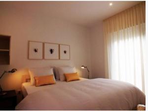 a bedroom with a large white bed with two orange pillows at Beach Bungalows - Casal dos Patos - Villa Sul in Lourinhã