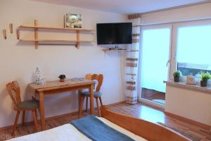 a room with a table and chairs and a tv at Pension Weigert in Bodenmais