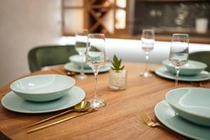 a wooden table with plates and wine glasses on it at Mila apartman in Prokuplje