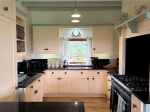 a kitchen with white cabinets and a sink and a window at Hartcliffe Retreat in Penistone