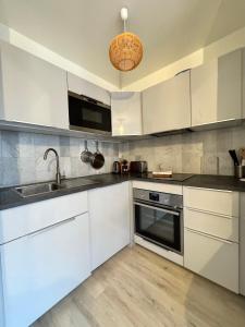 a kitchen with white cabinets and a sink at Le Nantais, centre de Rennes avec garage privé in Rennes