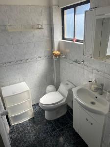 a white bathroom with a toilet and a sink at Casa en condominio equipada para 8 personas in Calama