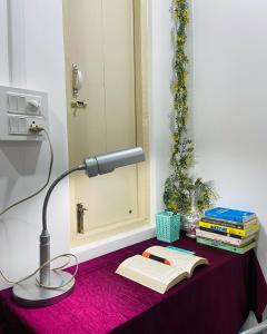 una lámpara sobre una mesa con un libro y libros en Nagaon Homestay, en Nowgong