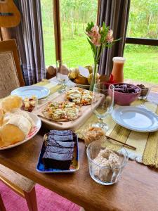 una mesa con platos de comida y copas de vino en Cabana com vista para o canyon, en Praia Grande