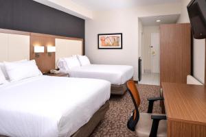 a hotel room with two beds and a desk at Holiday Inn Express Hotel & Suites Bonita Springs/Naples, an IHG Hotel in Bonita Springs
