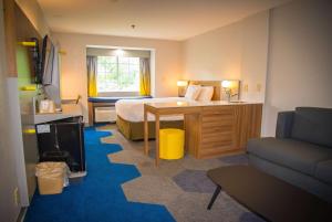 a hotel room with a bed and a couch at Microtel Inn & Suites by Wyndham Daphne in Daphne