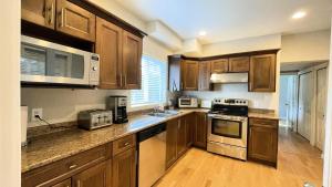 a kitchen with wooden cabinets and stainless steel appliances at King and Queen rooms -J&J Chilliwack in Chilliwack
