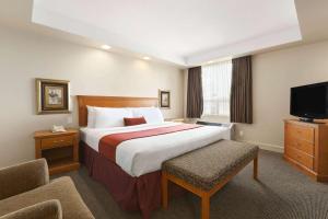 a hotel room with a bed and a flat screen tv at Travelodge by Wyndham Spruce Grove in Spruce Grove