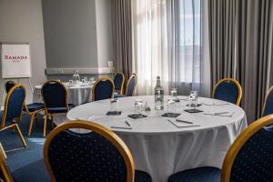 a meeting room with tables and chairs with a bottle of wine at Ramada by Wyndham Belfast in Belfast
