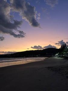 a view of a beach at sunset with the ocean at Casa pé na areia praia Garopaba in Garopaba