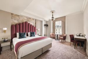 a bedroom with a large bed with a red headboard at voco The Clifton Folkestone by IHG in Folkestone
