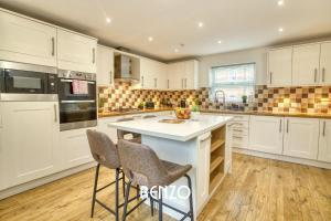 a kitchen with white cabinets and a island with bar stools at Incredible and Charming 4-bed Home in Lincoln by Renzo, Free Parking, Close to Lincoln Hospital! in Lincoln