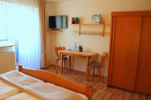 a bedroom with a table and a bed and a tv at Pension Weigert in Bodenmais