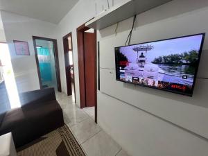 a flat screen tv on a wall in a living room at Tranquilidade e água fresca! in Tramandaí