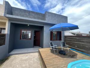 a blue umbrella and two chairs on a wooden deck at Tranquilidade e água fresca! in Tramandaí