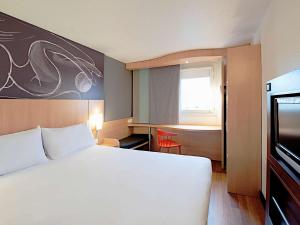 a hotel room with a large white bed and a window at ibis Paris Montmartre Sacré-Coeur in Paris