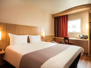 a hotel room with a large bed and a window at ibis Paris Montmartre Sacré-Coeur in Paris