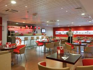a man standing in a restaurant with tables and chairs at ibis Paris Montmartre Sacré-Coeur in Paris