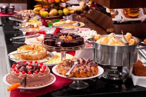 um buffet com muitos bolos e sobremesas diferentes em pratos em Hotel Estação 101 - Itajaí em Itajaí