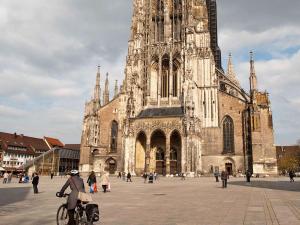 eine Frau auf einem Fahrrad vor einer Kathedrale in der Unterkunft Ibis Ulm City in Ulm