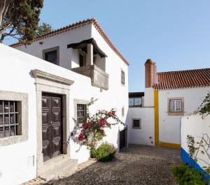 a white house with a black door and flowers at Torre de Maneys in Óbidos