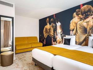 a bedroom with a bed and a painting of models at Mercure Paris Place d'Italie in Paris